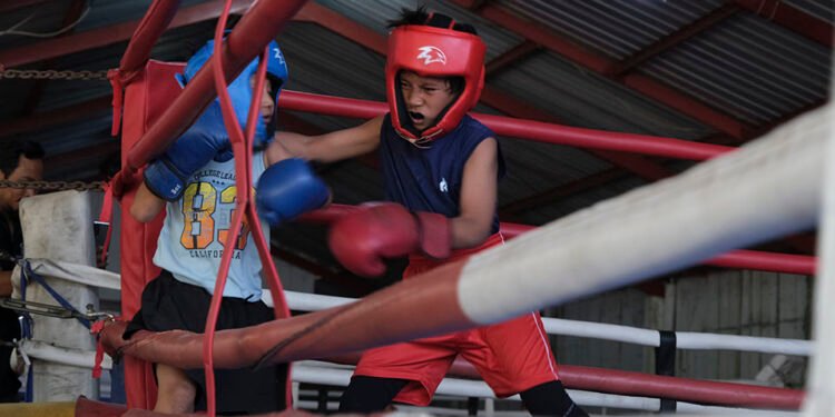 Two young fighters exchange punches inside a boxing ring during Born to Fight Vol. 2 at HAN Fighting Academy in Colomadu, Karanganyar.